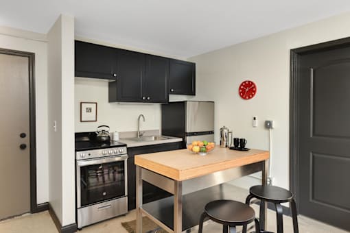 A modern kitchen with a wooden table and black stools.