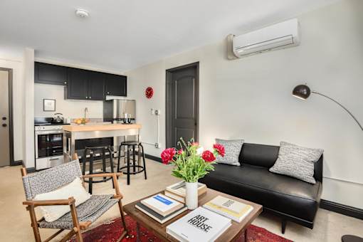 A black couch sits in a living room with a coffee table in front of it.
