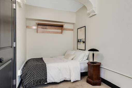 A bedroom with a bed, a lamp, and a picture on the wall.