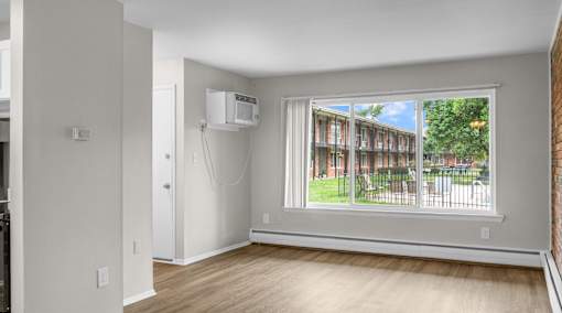 A room with a window showing a view of a residential area.