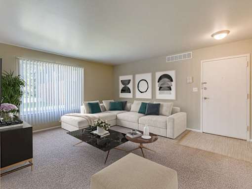 A living room with a white couch, a coffee table, and a potted plant.