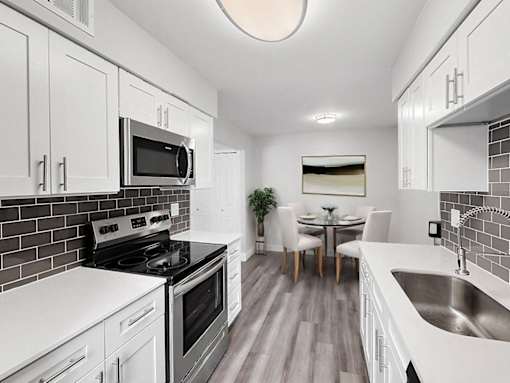 A modern kitchen with white cabinets and a black stove top.