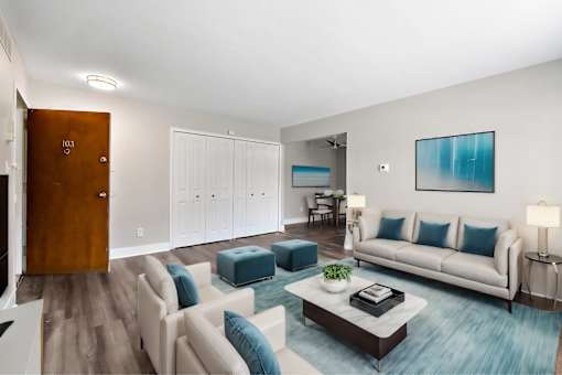 A living room with a white couch and a blue ottoman.