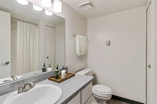 A white bathroom with a toilet, sink, and mirror.