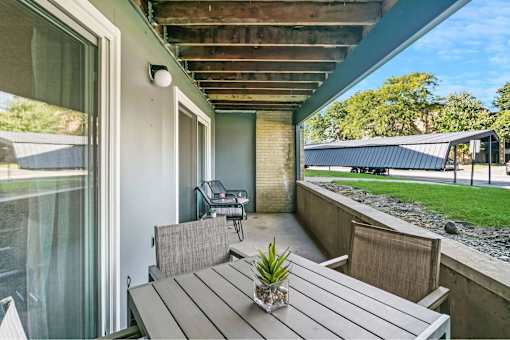 A wooden table with a potted plant on it sits on a patio.