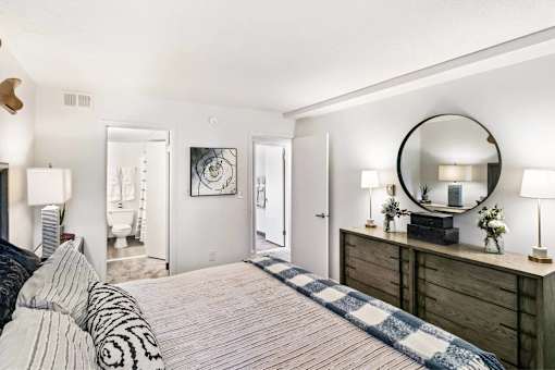 A bedroom with a bed, dresser, and mirror.