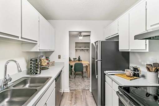 A kitchen with white cabinets and a black refrigerator.