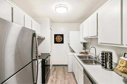 A kitchen with a stainless steel refrigerator and white cabinets.