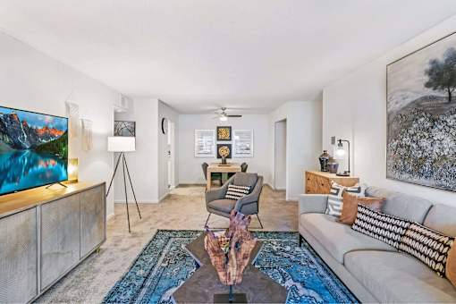 A living room with a grey couch, a coffee table, and a painting on the wall.