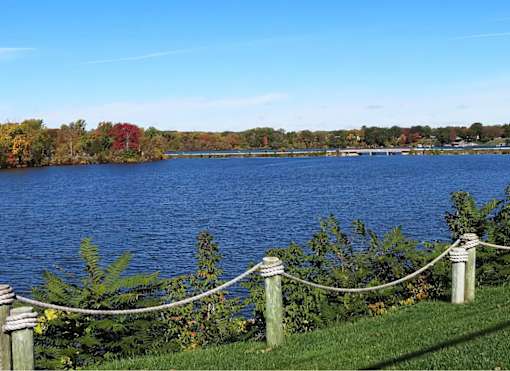 A lake surrounded by trees with a rope fence in the foreground.