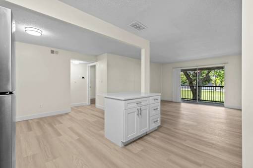 A white kitchen with wood flooring and a white fridge.