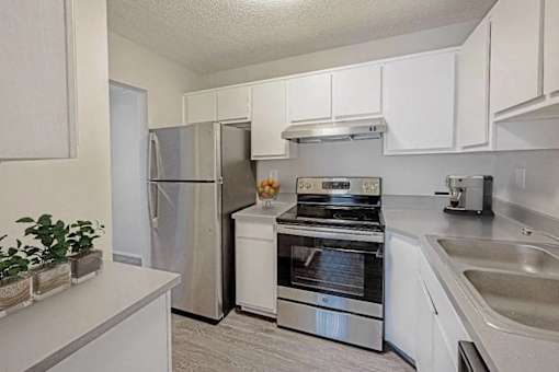 A kitchen with a refrigerator, oven, and sink.