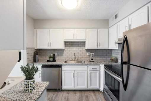 A kitchen with a black refrigerator and white cabinets.