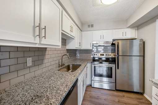 A kitchen with a stainless steel refrigerator, oven, and sink.