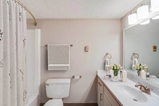 A white toilet sits next to a white sink in a bathroom.