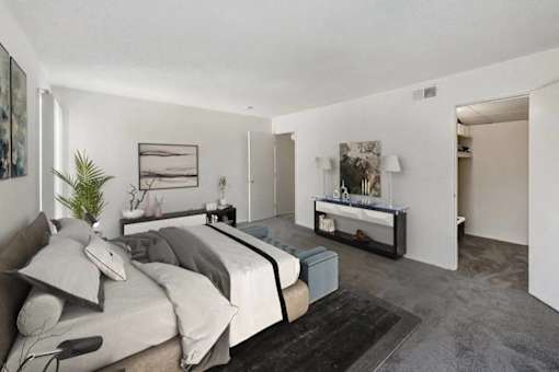 A bedroom with a large bed and a bench.