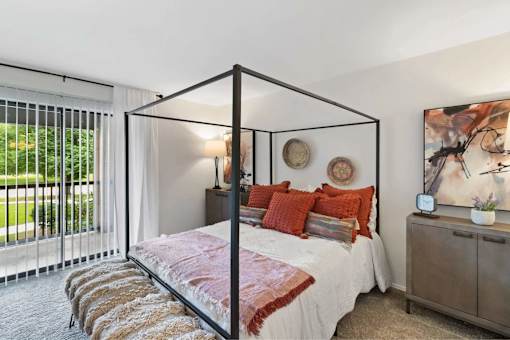 A bedroom with a four poster bed and a large window.