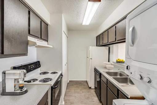 A kitchen with black cabinets and white appliances.