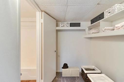 A room with a white door, a white bench, and a black hat on the bench.