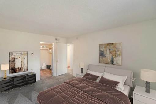 A bedroom with a large bed and a painting on the wall.