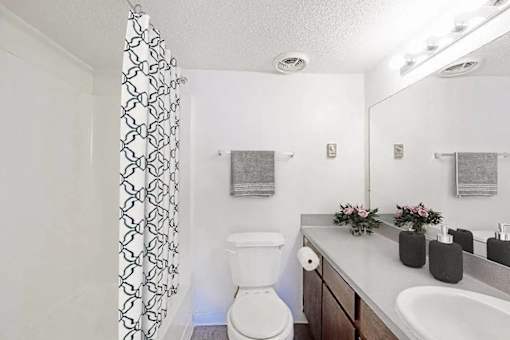 A white toilet sits in a bathroom next to a white sink.