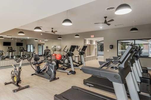 A gym with treadmills, elliptical machines, and other exercise equipment.