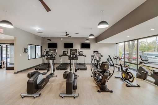 A gym with a variety of exercise equipment including treadmills, stationary bikes, and elliptical machines.
