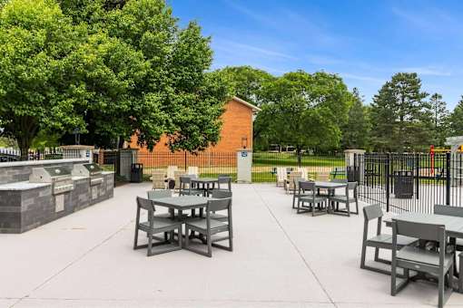 A park with tables and chairs and a fence.