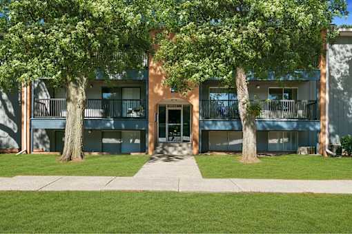 A building with a green lawn in front and trees on either side.