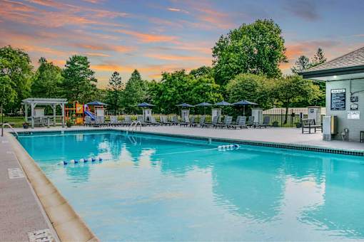 A large swimming pool with a sunset sky in the background.