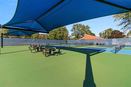 A tennis court with a blue canopy and green surface.