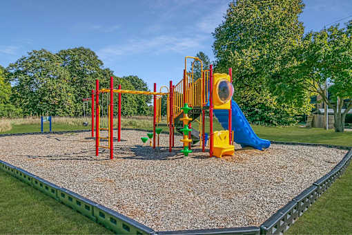 A playground with a yellow slide and a green slide.