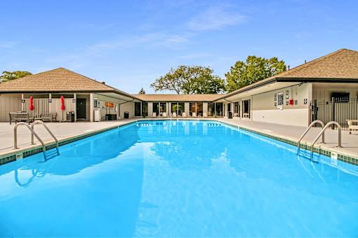 A large swimming pool in front of a building with a clear blue sky.