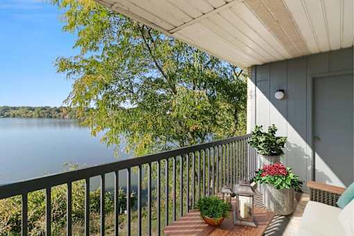 A balcony with a view of a lake and trees.