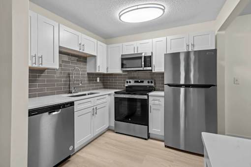A kitchen with stainless steel appliances and white cabinets.