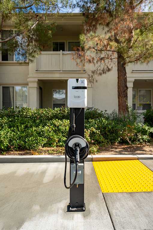 A parking meter is on the sidewalk in front of a building.