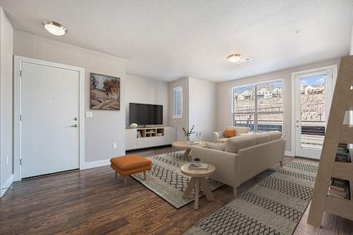 A living room with a couch, a chair, a coffee table, and a television.