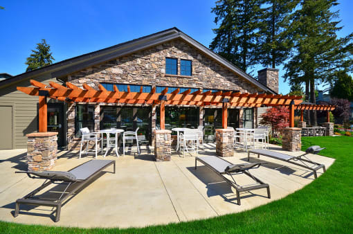 a patio with a pergola and lounge chairs on a sunny day
