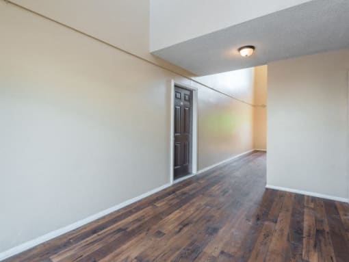 an empty room with white walls and wood flooring and a black door