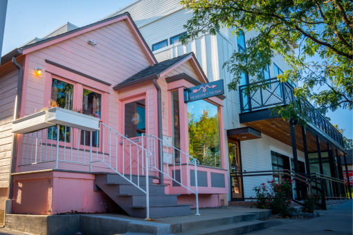 a pink building with stairs and a blue sign