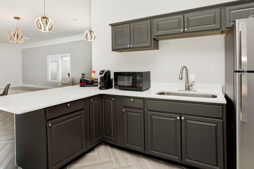 a kitchen with black cabinets and a sink and a refrigerator