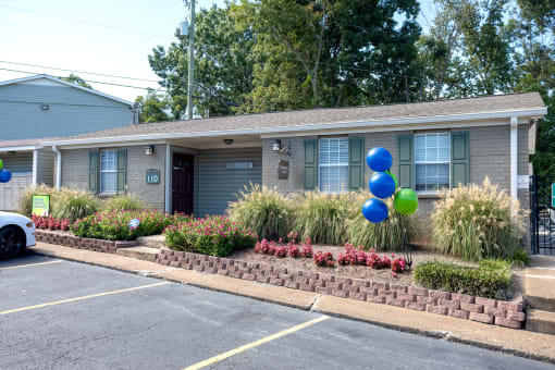 the front of an apartment with balloons in the front yard