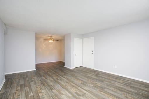 an empty living room with wood floors and white walls