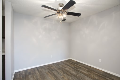 an empty living room with a ceiling fan and wood floors