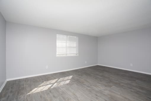 an empty room with wood floors and white walls and a window