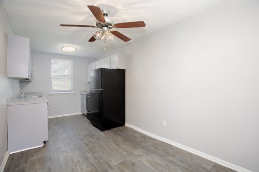 an empty kitchen with white walls and a ceiling fan