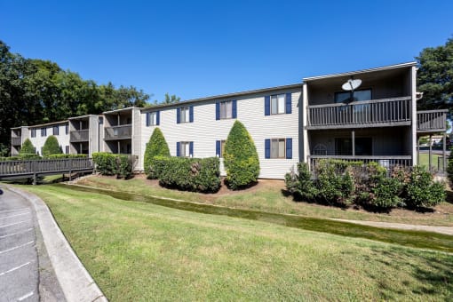 an apartment building with a lawn and trees in front of it