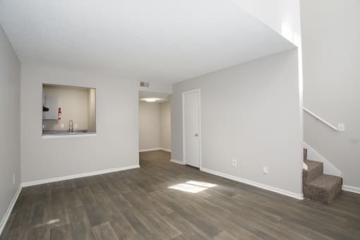 the living room and dining room of an apartment with white walls and wood floors