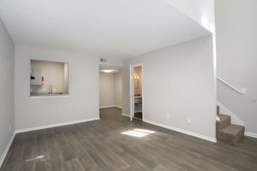 the living room and dining room of an apartment with white walls and wood floors