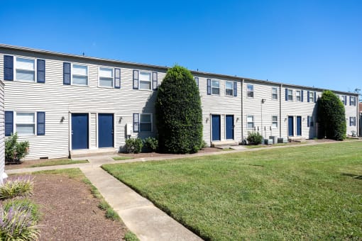 an apartment building with blue doors and white siding